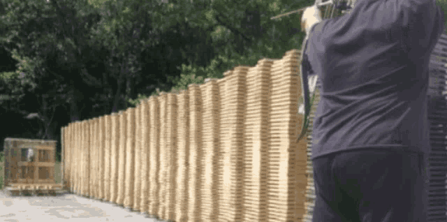 a man is standing in front of a fence made of wood
