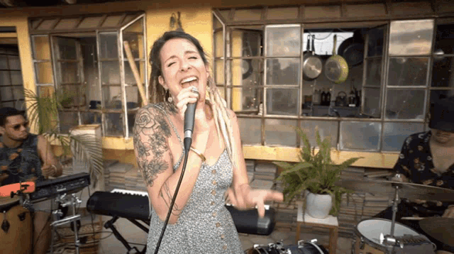 a woman singing into a microphone with a man playing drums behind her