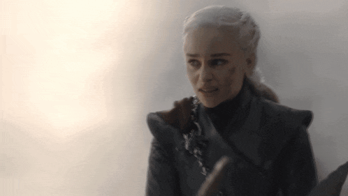 a close up of a woman holding a sword and looking at the camera .