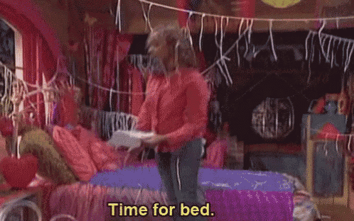 a woman in a pink shirt is laying on a bed holding a piece of paper and says `` time for school '' .