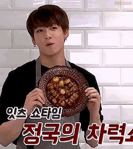 a young man in an apron is holding a plate of food in his hands