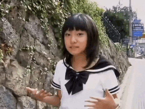 a young girl in a school uniform is standing on a sidewalk .