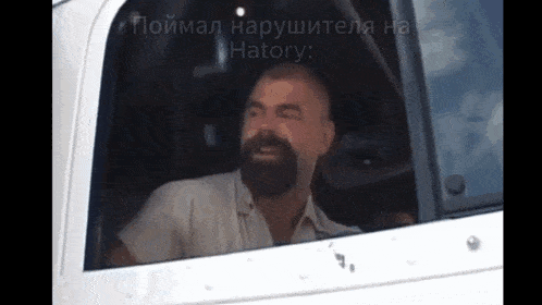 a man with a beard is sitting in the driver 's seat of a white truck