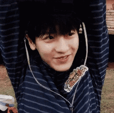a young man wearing headphones and a blue striped shirt is smiling .