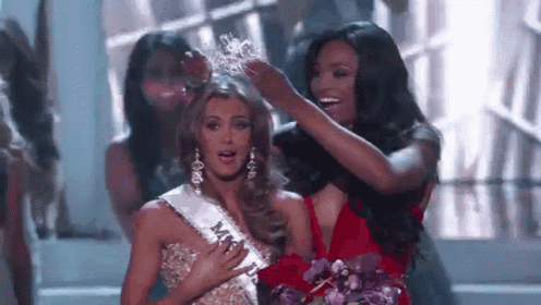 a woman in a red dress is putting a crown on another woman .
