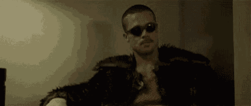 a man is wearing sunglasses and a fur coat .