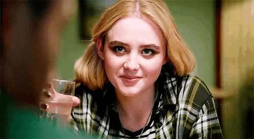 a woman in a plaid shirt is smiling while holding a glass of water .