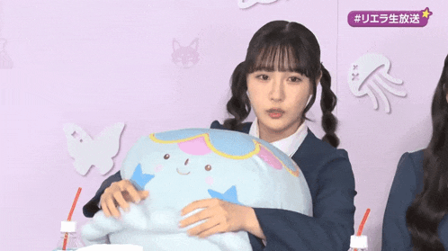 two girls are hugging a stuffed animal with a purple sticker that says # uea on it