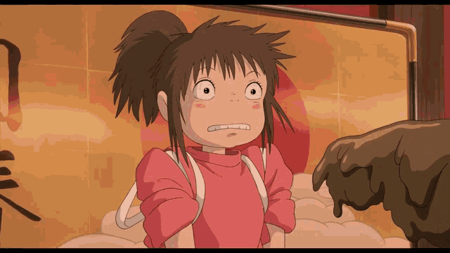 a girl in a pink shirt is standing in front of a wall with chinese writing