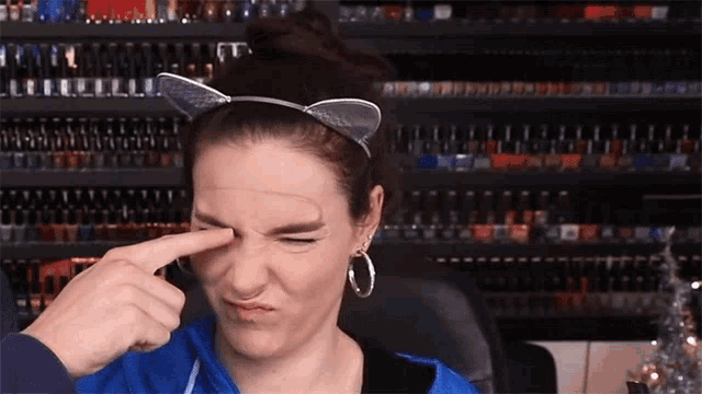 a woman wearing a cat ear headband wipes her eye