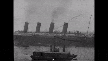 a black and white photo of a boat pulling a large ship in the water