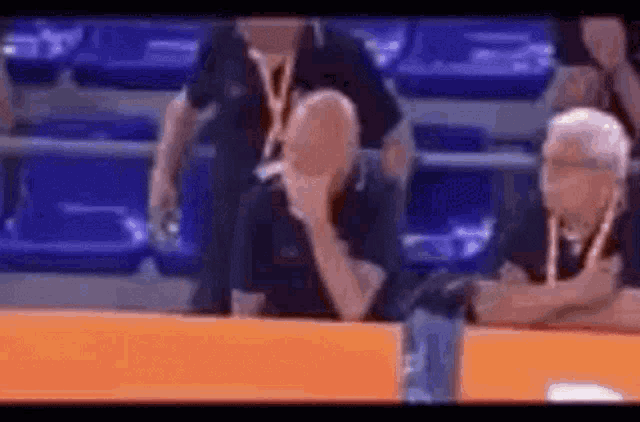 a group of men are sitting in a stadium watching a game .