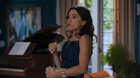 a woman in a blue dress is eating popcorn in front of a piano .
