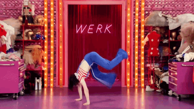 a woman does a handstand in front of a sign that says werk