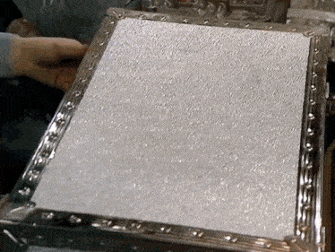 a person is holding a piece of metal with a silver frame