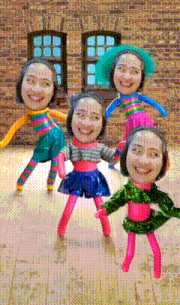 a group of dolls with faces on them are dancing in front of a brick building