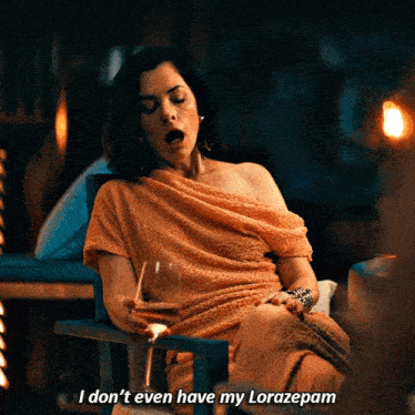 a woman sitting in a chair with a glass of wine says " i don t even have my lorazepam "