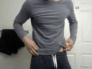 a man in a gray shirt and black shorts is standing in front of a door .