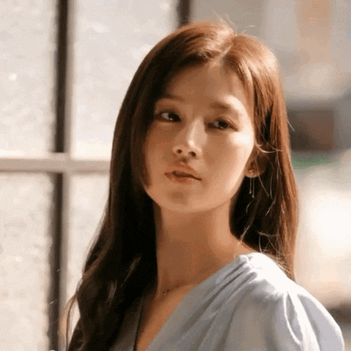 a woman with long hair is wearing a blue shirt and earrings