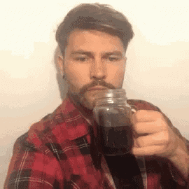a man in a plaid shirt is holding a mason jar of coffee .