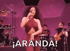 a woman is singing into a microphone on a stage while dancing .
