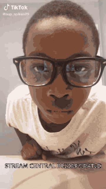 a young boy wearing glasses and a white shirt with the words stream central incorporated on it