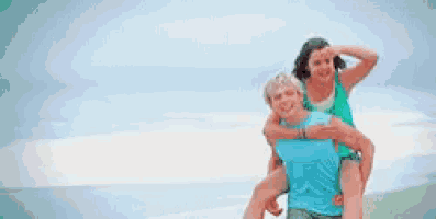 a man is giving a woman a piggyback ride on the beach