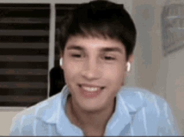 a young man wearing headphones and a blue shirt is smiling and looking at the camera .