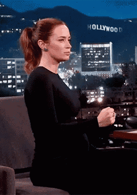 a woman is sitting in front of a sign that says hollywood