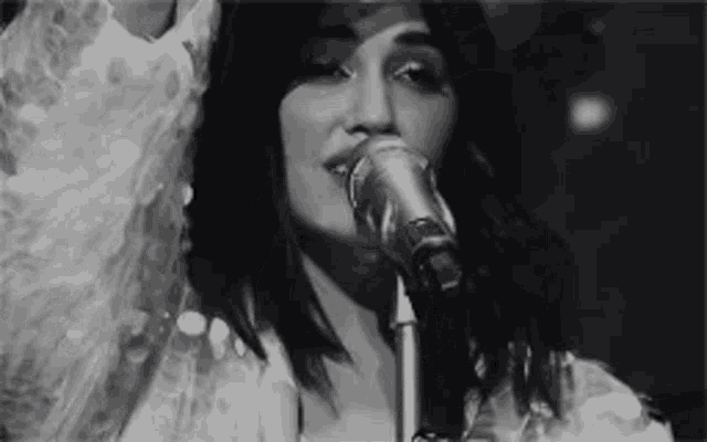 a woman singing into a microphone in a black and white photo .