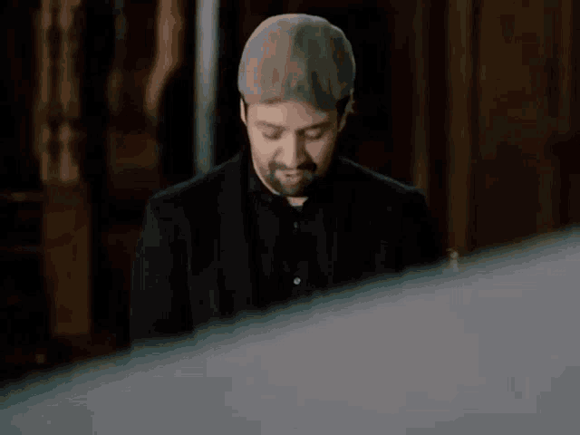 a man with a beard wearing a hat and a black shirt
