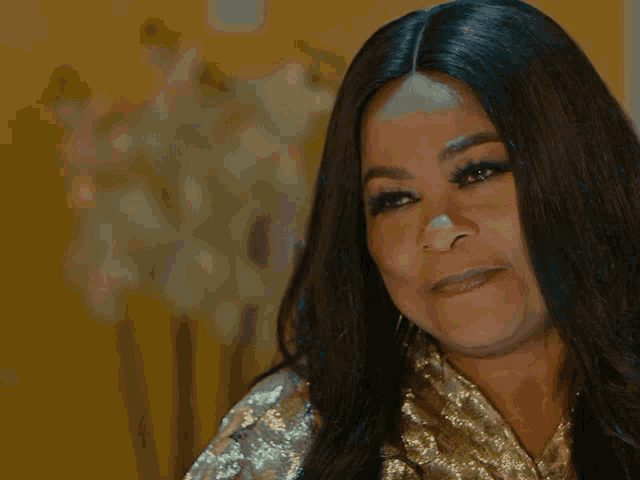 a woman with long black hair is wearing a gold dress