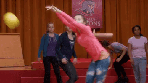 a girl in a pink shirt is throwing a ball in front of a sign that says " seus tons "