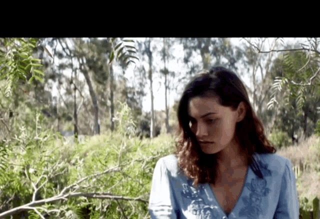 a woman in a blue shirt is standing in a field