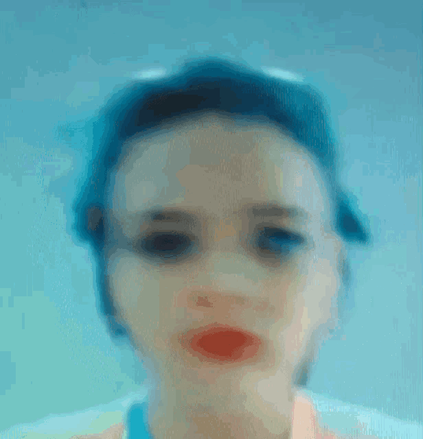 a blurry picture of a woman 's face with blue hair and red lips