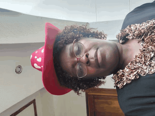 a woman wearing glasses and a red hat with white hearts on it