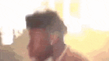 a blurry picture of a man 's face with a beard and a hat .