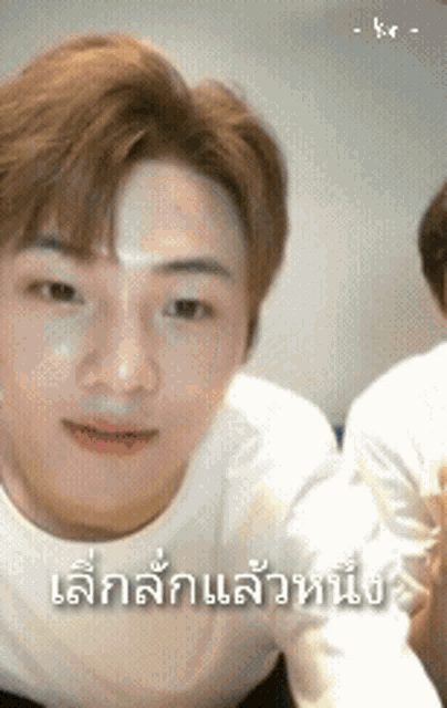 a man in a white shirt is looking at the camera with a foreign language written on his face .