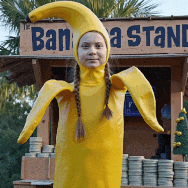 a girl in a banana costume stands in front of a sign that says the banana stand