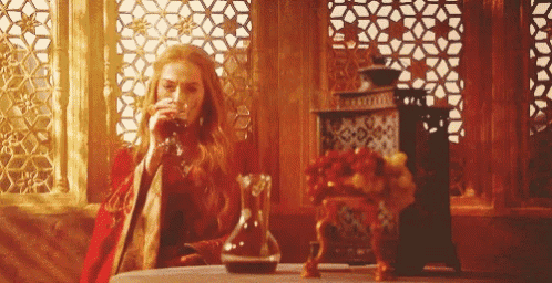 a woman in a red dress is drinking from a glass while sitting at a table .
