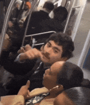 a man with a mustache is talking to a woman on a subway train .
