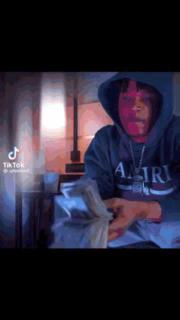a man in a hoodie holds a bunch of money