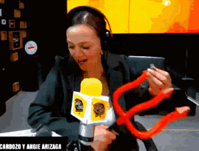 a woman is holding a red object in front of a microphone that says cardozo y angie