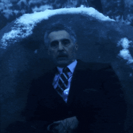 a man in a suit and tie stands in the dark