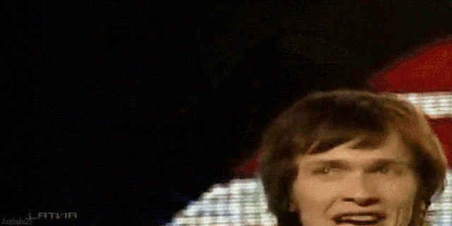 a man is singing into a microphone in front of a red white and blue background .