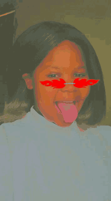 a woman wearing sunglasses with flames on them sticking her tongue out .