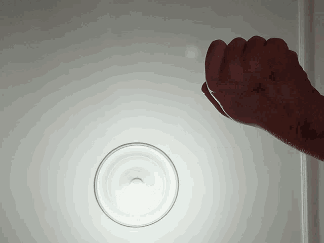 a person 's hand is reaching out towards a light on the ceiling