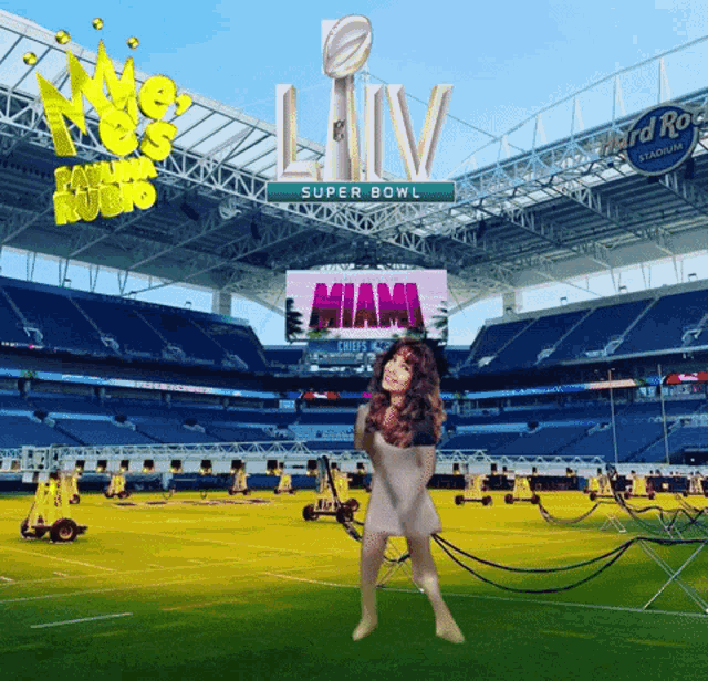 a woman stands in front of a large screen that says super bowl