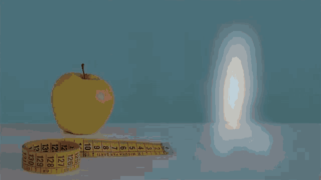 a yellow apple sits next to a yellow measuring tape with the numbers 12 to 29 on it