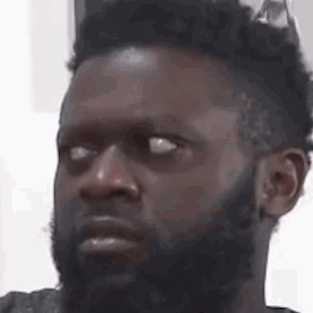 a man with a beard is making a funny face while looking at the camera .